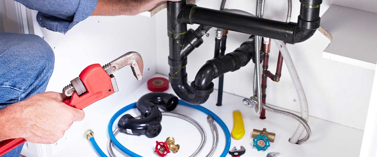 Image of a man performing a Pipe Repair under a sink